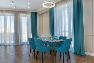 Elegant design of the dining room in a luxury apartment. Parquet floor, panoramic Windows. Beautiful table setting, soft blue chairs.