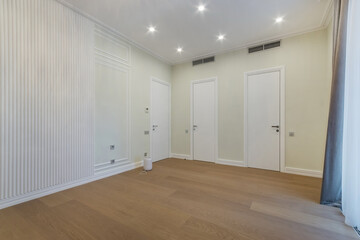 Obraz premium A room with light walls and white doors. Lamps built into the ceiling. Unfurnished.