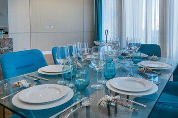Elegant table setting in the interior of luxury apartments. Bouquets of white flowers near the cutlery.