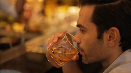 Sitting smart man drinking alone of cocktail Old fashioned waiting friends or couple at bokeh lighting at luxurious beverage counter nightclub at pub and restaurant on Friday meeting night. Vinosity.