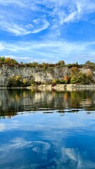 Vertical photo of Zalew Zakrzowek with rocks and sky reflected in blue water. Ideal for nature, travel, outdoor, and scenic landscape themes. Perfect for peaceful and serene visuals.