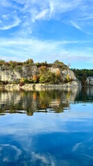 Vertical photo of Zalew Zakrzowek with rocks and sky reflected in blue water. Ideal for nature, travel, outdoor, and scenic landscape themes. Perfect for peaceful and serene visuals.