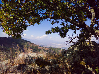 Civulization seen from the forest in the distance. Rocks and oak tree arch. Atecuaro, Michoacan.