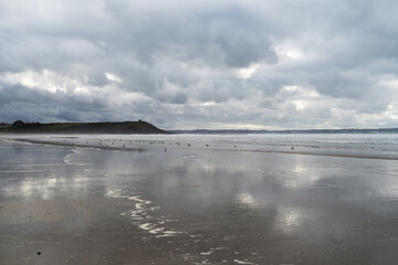 Reflets des nuages sur le sable mouillé de la plage de Lestrevet, créant un miroir naturel sous une lumière douce, sur une plage du Finistère en Bretagne.
