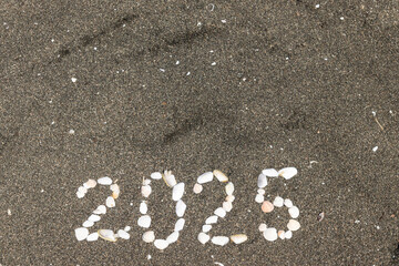 the figures of 2025 are laid out on the sand of shells