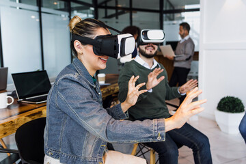 Group of young latin business people using virtual reality glasses during meeting testing VR headset at office in Mexico Latin America. hispanic people at working at job