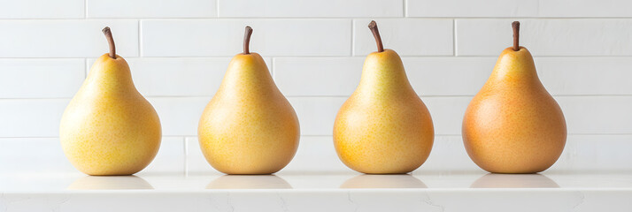 A row of pears sitting on a white surface with a white tiled background, with a gradient of yellow and orange.
