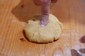 Hand pressing dough on wooden surface
