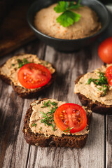 Rustic Pate, man smear on Black Bread with Fresh Herbs and tomatoes