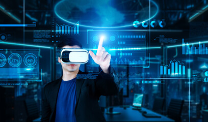 Project manager with VR goggles pointing financial chart and glowing blue light at office. Skilled businessman checking and planning marketing strategy by using data from augmented reality. Ingenuity.