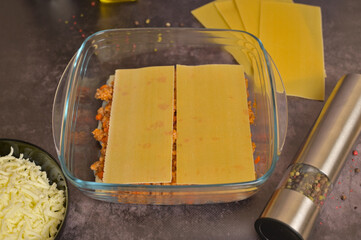 Homemade lasagna cooking preparation. Lasagne pasta sheets, Bolognese and béchamel sauces in a...