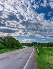Road with a few trees in the background and a cloudy sky
