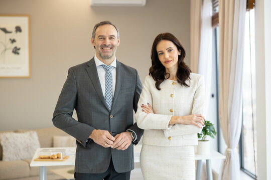 Two stylish professionals, engaged in conversation, exuding confidence and charisma in a bright office interior.