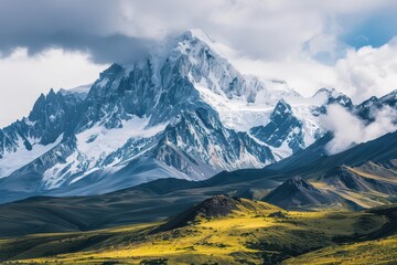 Fototapeta premium Majestic mountain range with snow-capped peaks and dramatic clouds under a clear blue sky at midday