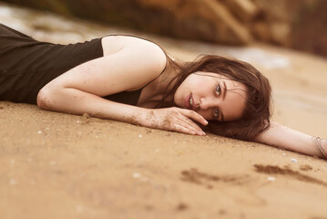 close-up of a brunette girl lying on the sand at the sea beach
