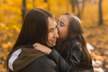 Little girl playing with mother in the autumn park