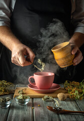 Hands carefully prepare a fragrant herbal tea in a charming kitchen, steam rising from the pink cup...