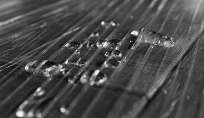 Closeup Black And White Image Of Folded Plastic With Liquid Drops On Wet Surface 
