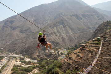 mujer haciendo deporte extremo canopy en la montaña con accesorios de seguridad y casco color verde