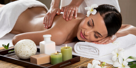 Obraz na płótnie Canvas A woman enjoying a relaxing massage in a serene spa setting with candles, soaps, and flowers, symbolizing self-care, wellness, and tranquility in a peaceful environment.