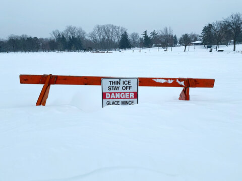 Thin Ice Danger Sign on Snow-Covered Frozen Lake