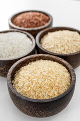 different kinds of asian rice grains in bowls on white background