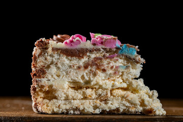 Piece of Kyiv cake with chocolate cream and decorative top on black background, closeup