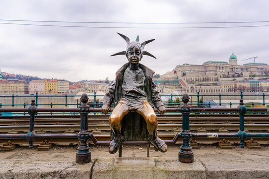 Budapest, Hungary - Feb. 2, 2025: This Little Princess bronze statue (Kiskiralylany) by Laszlo Marton sits on the railing of the Danube Promenade.