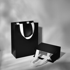 A stylish black paper shopping bag with elegant white ribbon handles, perfect for luxury packaging and branding