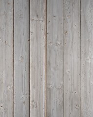 a wooden surface, showcasing a vertical layout of four wide planks. The wood has a weathered and rustic appearance, with a predominantly light gray color, interspersed with subtle variations in tone. 
