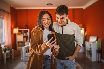 youth couple boyfriend and girlfriend use mobile phone for fun at home