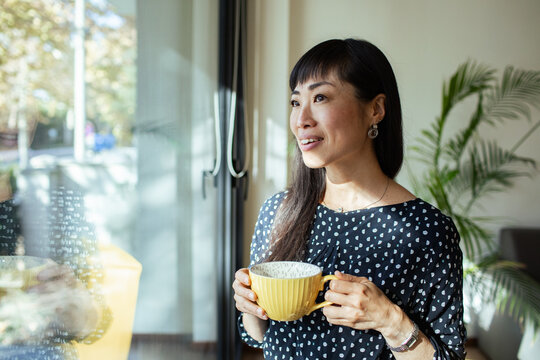 Asian woman a warm cup of coffee by the office window