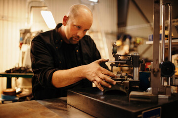 Middle aged caucasian man working with a machine in a workshop factory