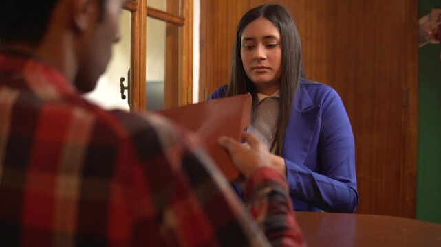 Mujer latina vestida formalmente para una entrevista de trabajo entregando su curr&iacute;culum con una expresi&oacute;n preocupada