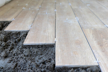 Worker use plastic tile spacers for accurate alignment of floor tiles, Semi-dry floor screed.