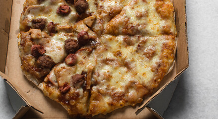 Overhead view of a large pizza in a box, top view of a cheese and sausage pizza in a box