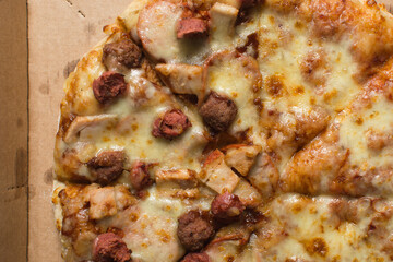 Overhead view of a large pizza in a box, top view of a cheese and sausage pizza in a box