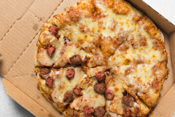 Overhead view of a large pizza in a box, top view of a cheese and sausage pizza in a box