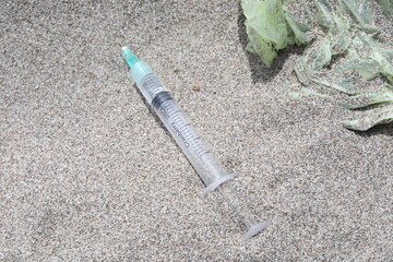 syringe and beer bottle on the beach