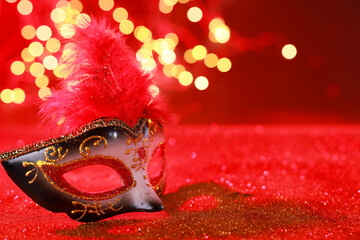 Beautiful carnival mask on shiny red background, bokeh effect. Space for text