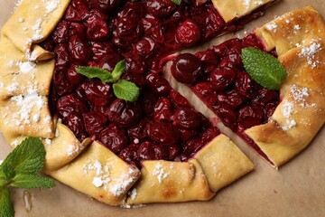 Tasty galette with cherries and mint on table, closeup