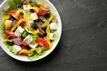 Delicious fresh Greek salad in bowl on black table, top view. Space for text