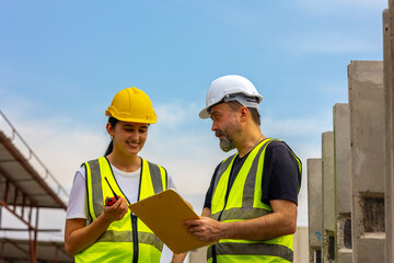 A male engineer gives safety advice to his female trainee in a floor making factory. Senior supervisor discusses with his assistant or clerk checking the concrete wall production system