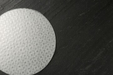 Stack of edible rice paper sheets on dark textured table, top view. Space for text