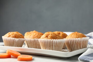 Tasty carrot muffins and cut vegetable on white marble table, closeup