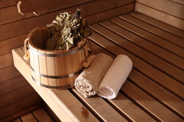 Bucket, whisk and towels on wooden bench in sauna