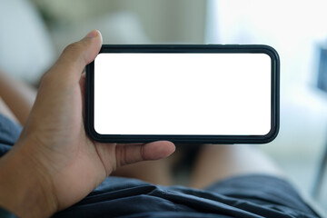 Hand holding a smartphone in horizontal orientation with a blank white screen, for mockups or app presentations.