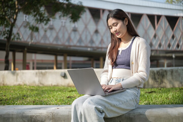 University student working on a laptop outdoors in a sunny campus. Education concept.