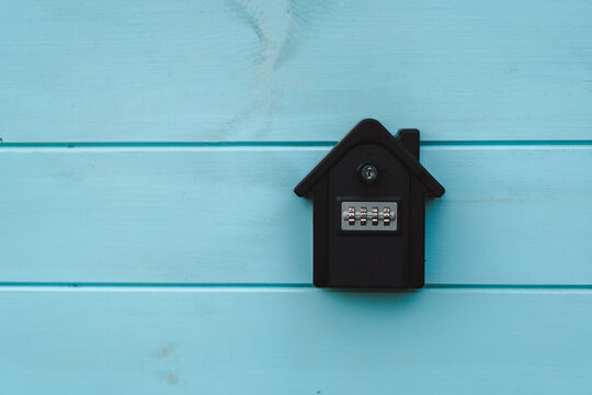 Combination lockbox mounted on a blue wooden wall for safe key storage at a propertys entrance