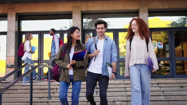 Team of diverse genders and races students smiling walking down the stairs leaving the university building conversing happy. Lifestyle Generation z young joyful friends together on campus outdoor